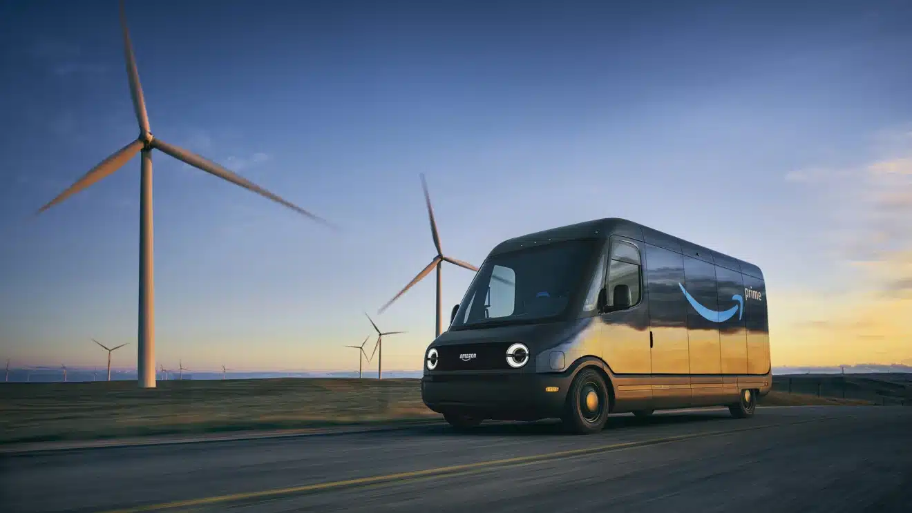 An electric bus drives past wind turbines during sunset, showcasing sustainable transportation and renewable energy. Note: Without the actual image, I've provided a description based on a typical scene that might match the context given by the user. If you did provide an image and this does not match, please let me know, and I can tailor the description accordingly.