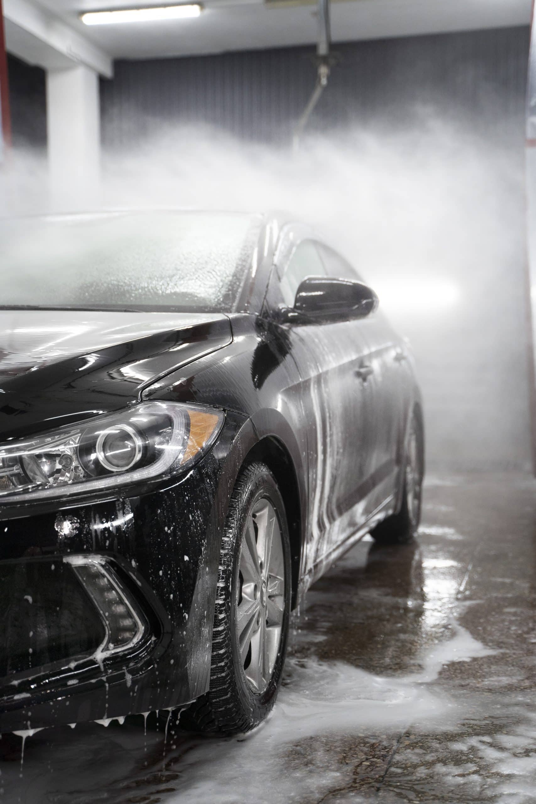 A car receiving a high-pressure foam wash in an automated car wash facility.