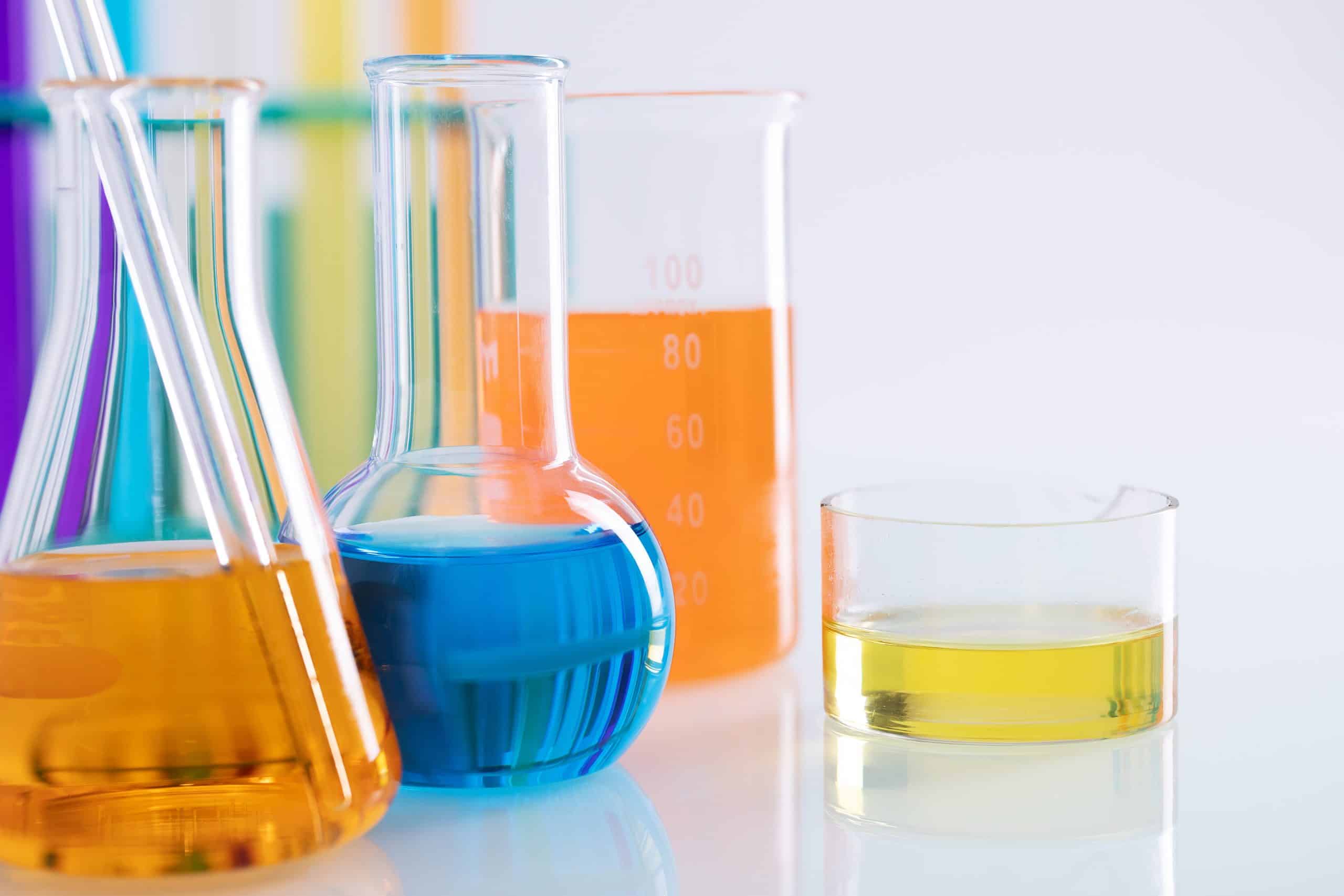 Colorful liquids in laboratory glassware on a white background, suggesting a chemical or scientific experiment.