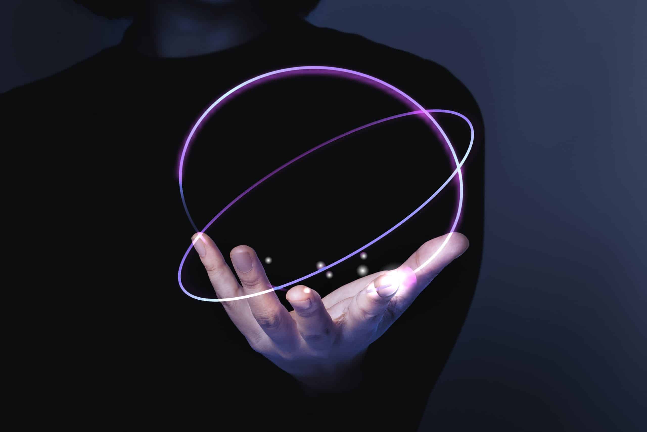 A person is holding a digitally-imposed, glowing purple ring orbiting around their hand, creating a futuristic effect.
